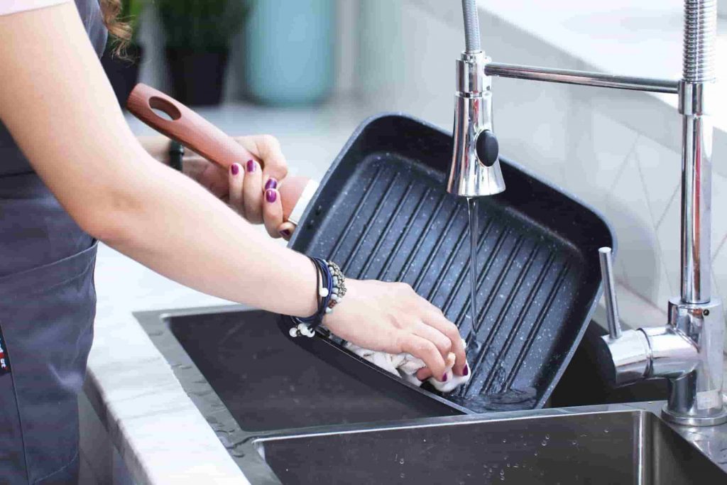 a person washing their pan in a kitchen sink