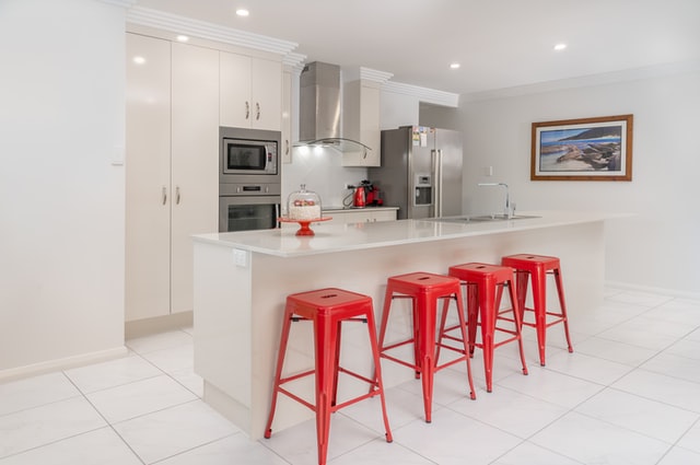 Mediterranean Style Kitchen, all-white kitchen featuring stainless steel appliances and red chairs