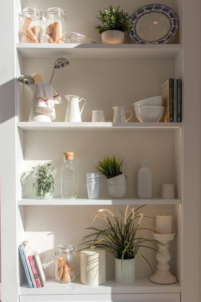 a well arranged pantry with all kitchen items are arranged on shelves